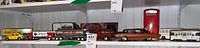 Shelf display showing collection of toy cars and trucks including Volkswagen, Coca-Cola van, trailer, and others.