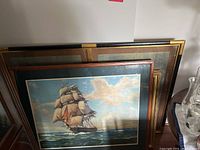 Set of four large framed artworks, one featuring a sailing ship on ocean and three with Chinese Song Dynasty style artwork.