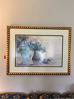 Photo of the framed hydrangea floral print hanging on the wall, showing the heavy gold frame and the artwork inside.