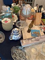 Image showing assorted glass bowls, blue and white ceramic teapot, marble rolling pin box, knife block, decorative figurines, and trays on table.