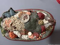 Top view of June McKenna signed figurine showing seated man with beard in richly detailed attire holding paint palette, on textured base with various accessories.