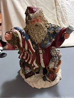 Image of June McKenna signed Santa Claus figurine from front, showing detailed face, beard, and Americana theme with flag and toys at base.