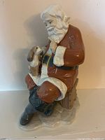 Photo of Lladro Santa's Little Secret Christmas figurine showing Santa seated with dog on lap