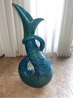 Front angle view of the ceramic vase showing glossy blue-green glaze and serpentine snake shape with coiled tail handle.