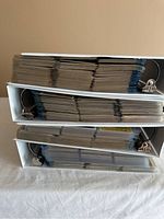 Side view of four white binders filled with baseball cards in plastic sleeves.