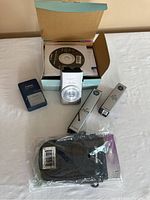 Canon PowerShot ELPH 330 HS camera front with box, battery charger, battery, DVD, lens cleaning kits, and camera case