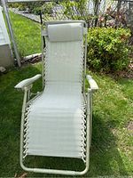 Anti-gravity lounge chair with light-colored mesh fabric and attached headrest cushion. Metal frame with armrests.
