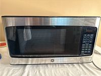 Front view of GE microwave JES1145SH1SS showing stainless steel body, large window door and digital keypad.