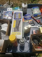 Photo showing various shed miscellaneous items including plumbing fittings, hand tools, adhesive spray can, boxes with hardware and plumbing parts