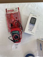 Wide view showing Craftsman multimeter with attached probes, still in partial packaging, next to boxed power meter on white surface.