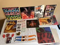 Photo showing various Rolling Stones albums, magazines, stickers, concert tickets, posters, a patch, and other memorabilia spread out on a flat surface.