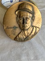 Front side of bronze medallion with relief portrait of Ted Williams wearing a baseball cap and showing his number 9.