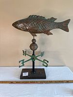 Full front view of fish weathervane on stand showing overall shape and patina