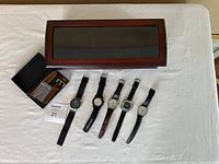 Full lot overview showing five watches laid out, wooden display case, and boxed extra leather strap.