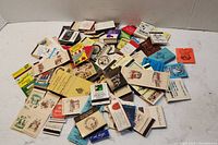 Top view of scattered assorted matchbooks showing different colors, logos, and texts.