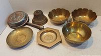 Photo of brass and copper lot showing five brass bowls, a copper pot with ornate lid, and a brass bell with handle.