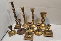 Full view of nine brass candle holders arranged on white background