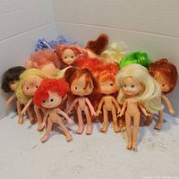 Front view showing the lot of 12 small nude dolls with different hair colors and facial features.