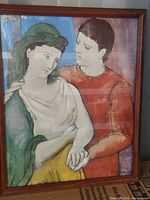 Full view of framed Picasso-style art print showing two figures, one in green and white clothing and the other in orange/red, with a wooden frame.