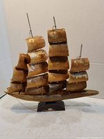 Front view of the model ship with multiple horn sails and copper masts on a dark base.