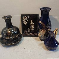 Front view of three dark blue vases, one octagonal plate, and one standing decorative box with gold trim