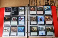 Open binder showing two pages filled with Magic The Gathering cards in plastic sleeves, featuring various card types and colors.