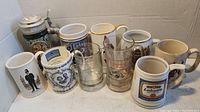 Front view of the 10 mugs and steins arranged showing detailed designs and range of styles