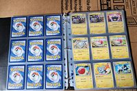 Photo of black binder page showing backs of Pokémon cards in protective sleeves.