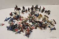 Overview of mixed metal and plastic soldier figurines including infantry, cavalry, and artillery figures spread on a surface