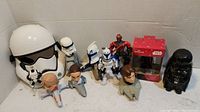 Photo of Star Wars lot showing kids Stormtrooper helmet mask, various action figures including clone troopers, Sith character, Darth Vader flashlight figure, character bobbleheads, and boxed collectible.