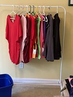 Full view of all 11 clothing items on rack showing 9 tops in various colors and 2 dark jackets.