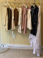 Clothes hanging on rack including pants, tops, skirt, and dress with visible tags