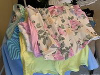 Pile of 10 bustiers and crop tops in various pastel colors and floral patterns, displaying the variety included in the lot.