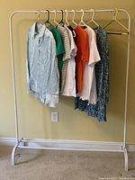 Lot of 8 ZARA tops hanging on a white clothes rack, showing variety of colors and styles.