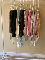 Photo showing 10 pairs of Zara women's pants hanging on a clothing rack with hangers. Various colors and styles visible with tags attached.