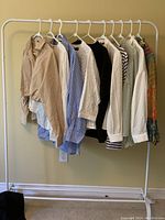 10 new women's tops from Zara hanging on clothing rack in various styles and colors including beige, white, blue, black, and patterned.