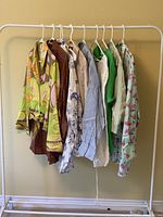 Photo of 10 tops hanging on rack showing various colors and styles.