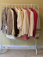 Photo showing 10 hanging Zara jackets of various styles and colors including houndstooth, cream, pink, and beige with stripe accents.