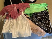 Photo showing lace mauve bralette, white smooth shorts, green bra, black and white striped bra, blush pink lace-trimmed shorts.