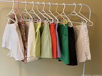 Ten pairs of women's shorts from ZARA hanging on rack, showing variety of colors and patterns including white eyelet, printed, solid colors