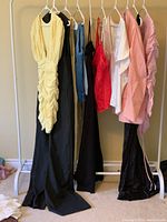 Full view of hanging clothing items showing dresses, tops, pantsuit, and jacket in varied colors including yellow, black, white, pink, red, and blue.