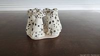 Front and side view of the ceramic Dalmatian dogs candle holder showing the detailed sculpting and painting of five dogs sitting in a circle.
