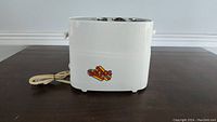 Left side view of white hotdog toaster showing power cord and 'Hot Dog Toaster' logo.