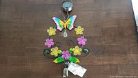 Full view of outdoor solar butterfly light showing colorful butterfly, flowers, solar panel, and hanging hook