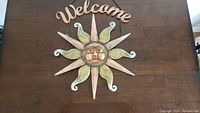 Close-up of sun face and 'Welcome' sign on wooden background.