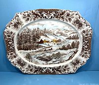 Full view of the large oval platter displaying detailed winter holiday scene with pinecone-acorn border.