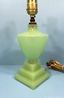 Front view showing square stepped base and vase-shaped body in pale green jadeite glass.