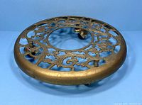 Top-down view of vintage brass rolling plant stand showing intricate openwork brass design and trio of caster wheels below.
