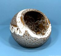 Photo showing the textured and mottled brown and white ceramic ashtray from an angled side view, highlighting the glaze details and overall shape.