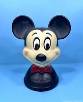 Front view of vintage Mickey Mouse plastic coin bank with detailed face and bow tie.